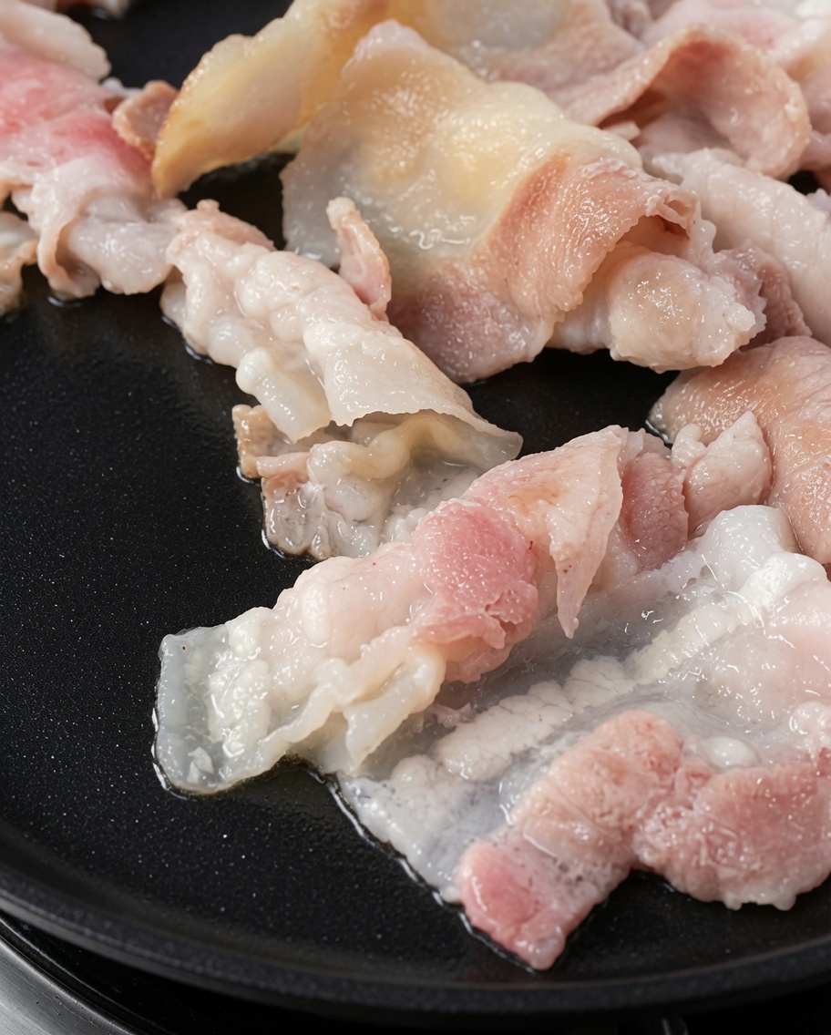 Fette di pancetta grigliata dorate su una piastra calda.