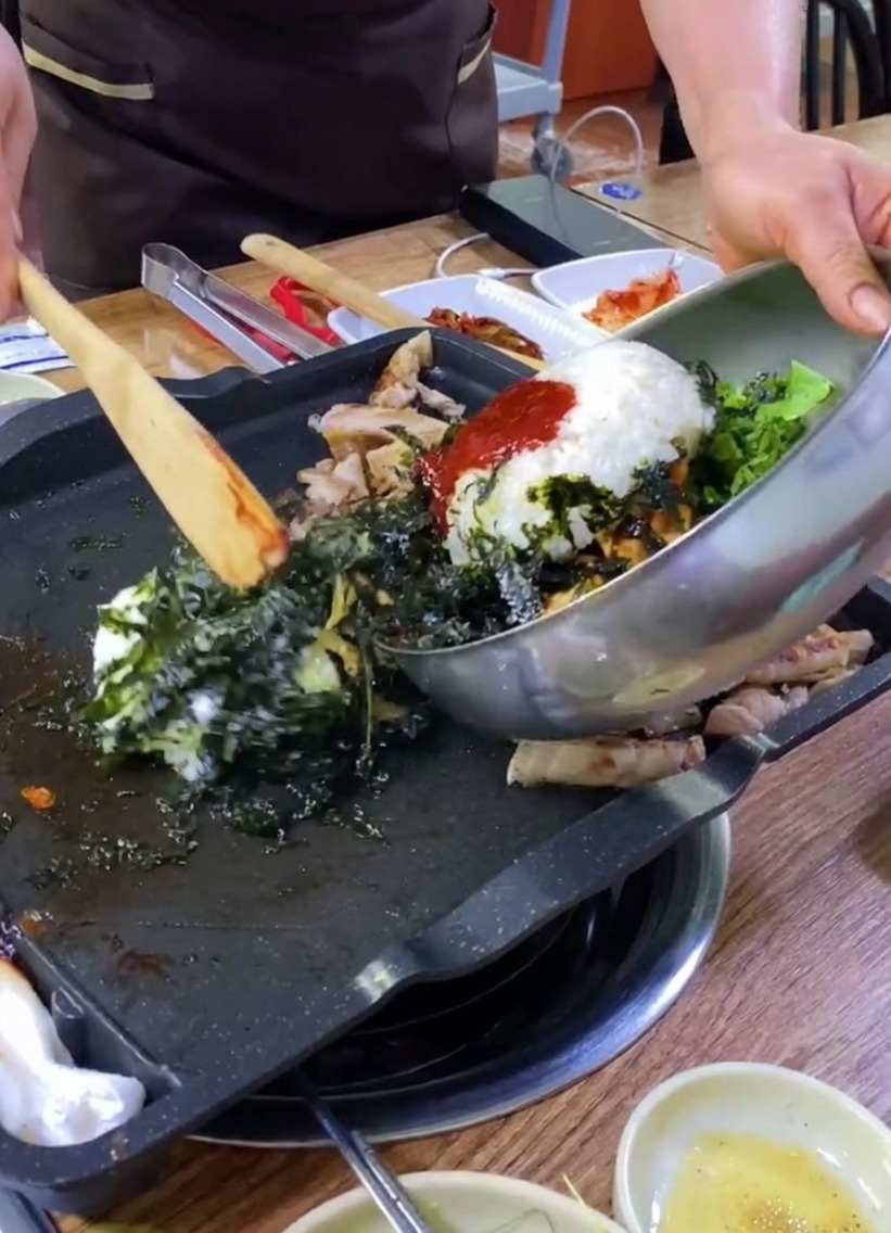 Riso, verdure e alghe versate da una ciotola su una piastra con la pancetta.