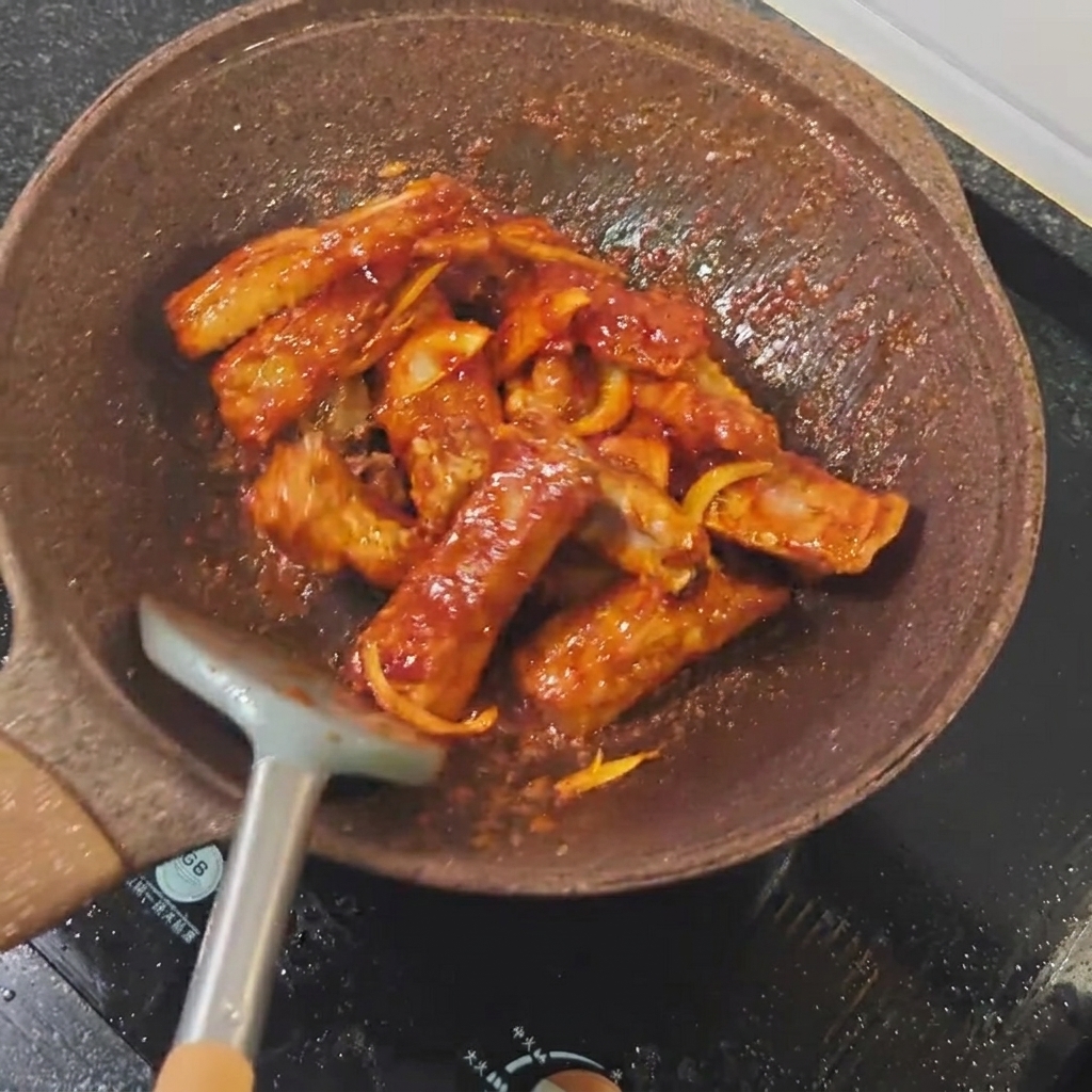 Salsa di soia chiara versata sulle costine in padella.