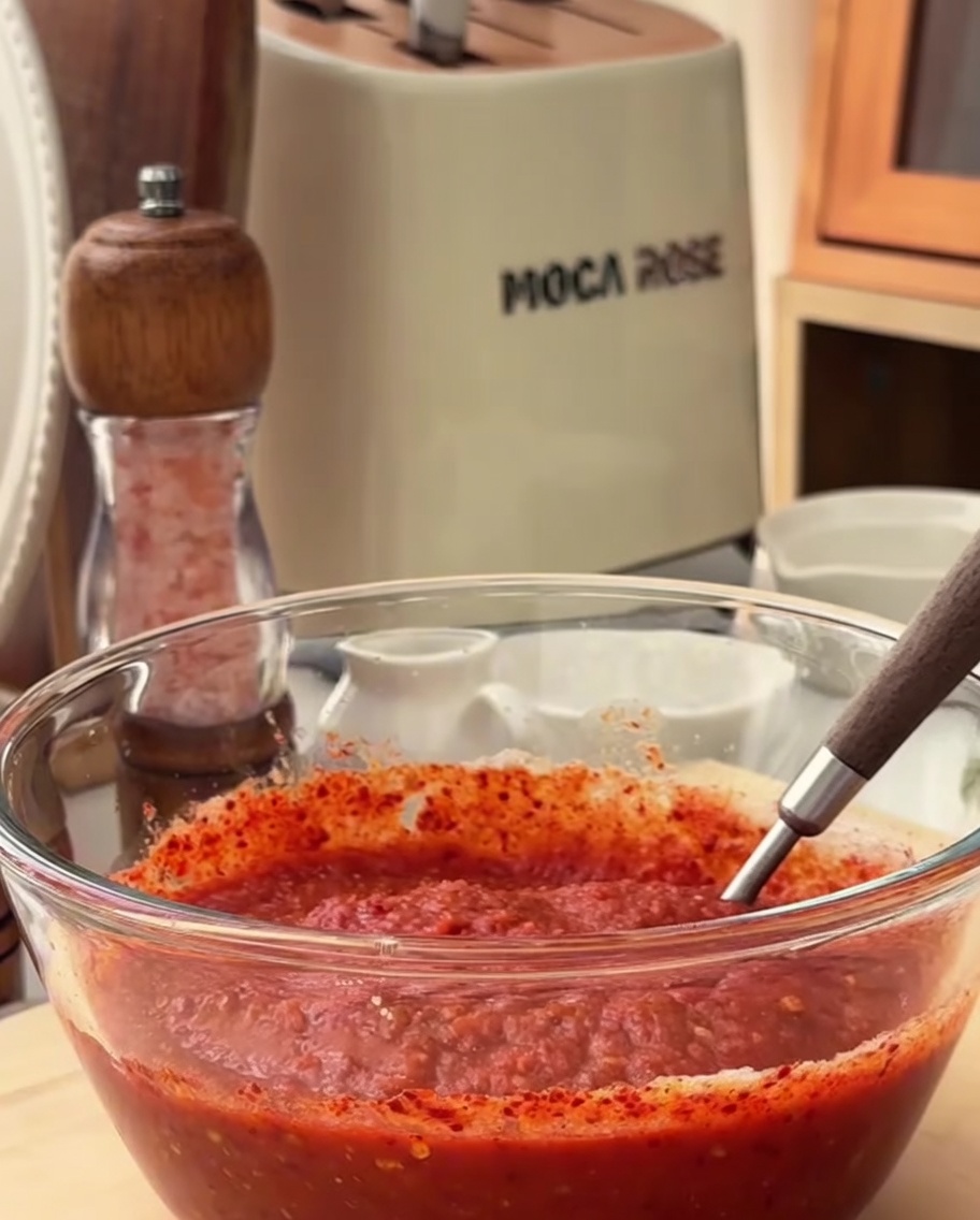 Un primo piano degli ingredienti della marinata speziata mescolati insieme in una ciotola di vetro.