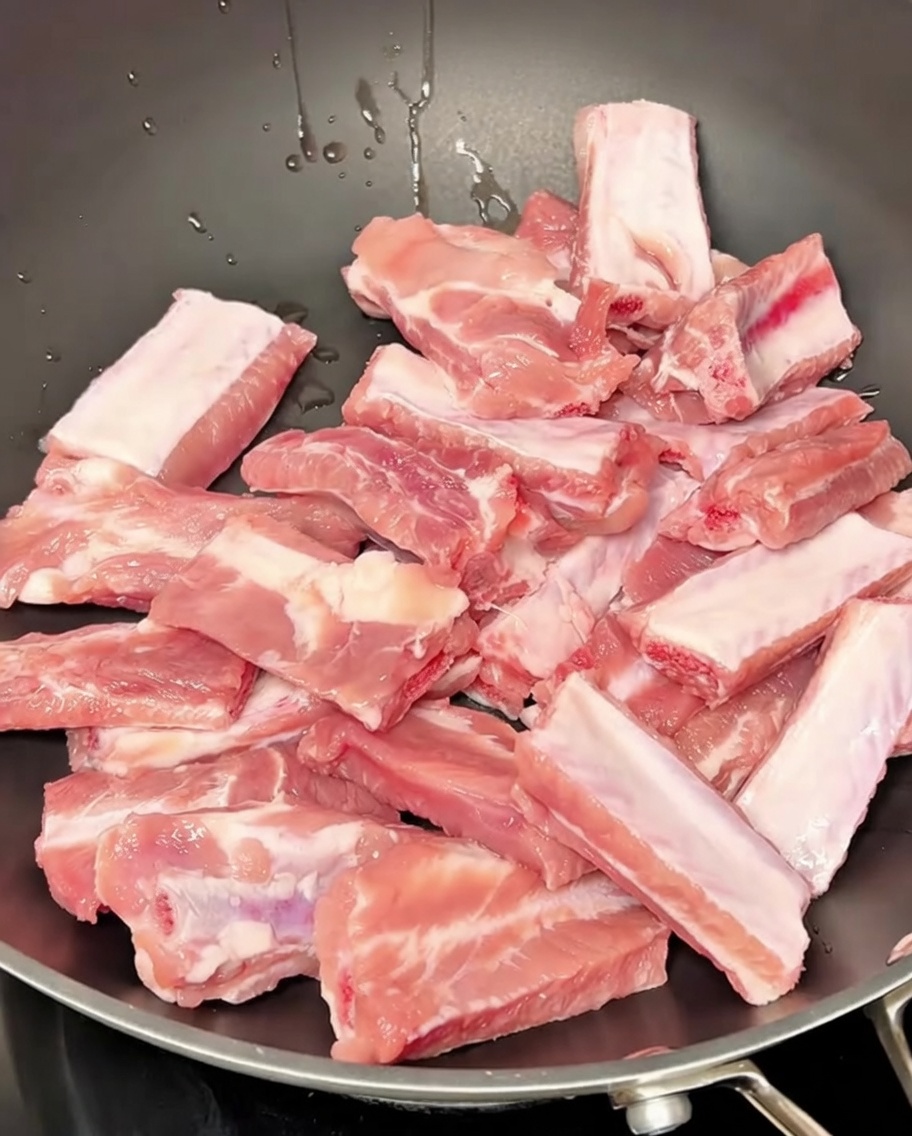 Costine di maiale che sobbollono in una pentola dacqua con aromi.