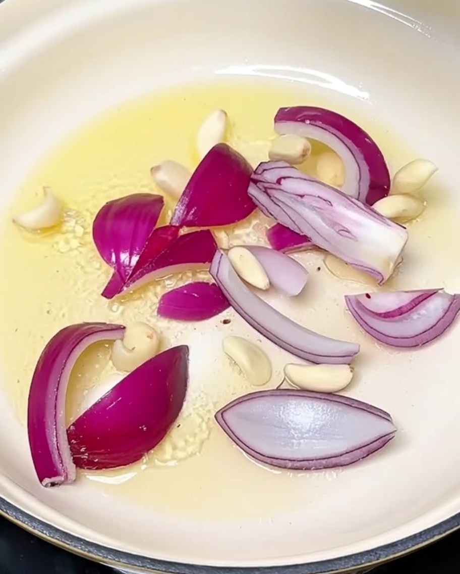 Cipolla affettata e spicchi daglio che soffriggono in olio caldo.