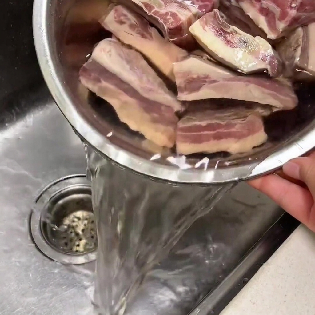 Costine di manzo in ammollo in una ciotola di acqua fredda nel lavandino della cucina.