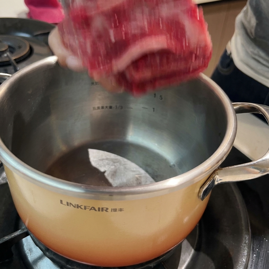 Costine di manzo in ammollo in una pentola di acqua fredda con aromi, pronte per il processo di sbollentatura.