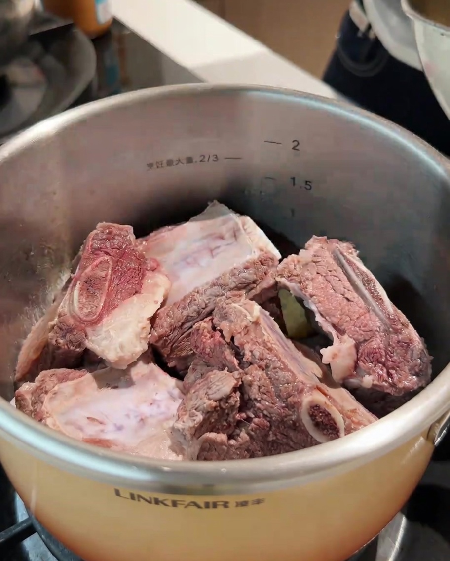 Costine di manzo sbollentate e una selezione di spezie intere aggiunte alla pentola.