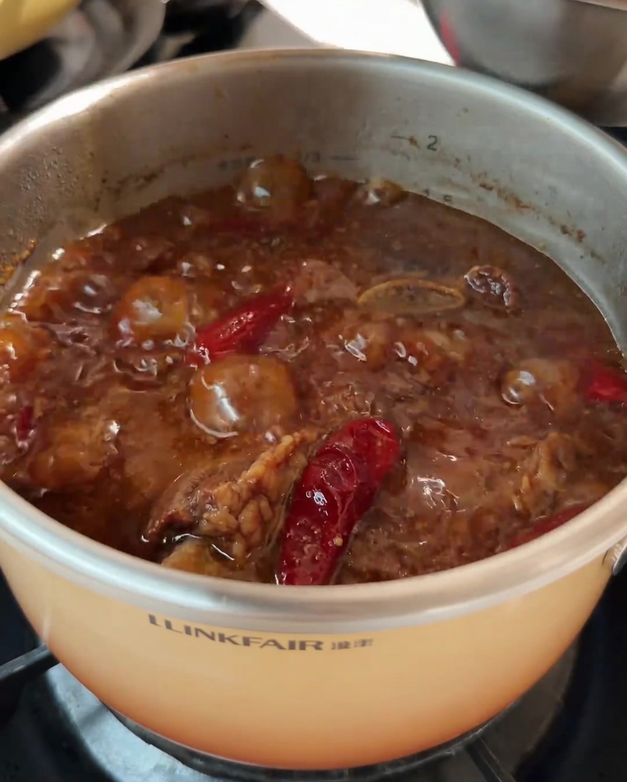 Carote tagliate a pezzi aggiunte alla pentola con la zuppa di costine di manzo in cottura.