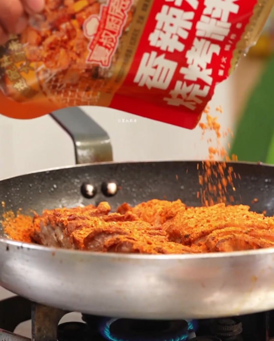 Carne condita con spezie e aromi in una padella calda.