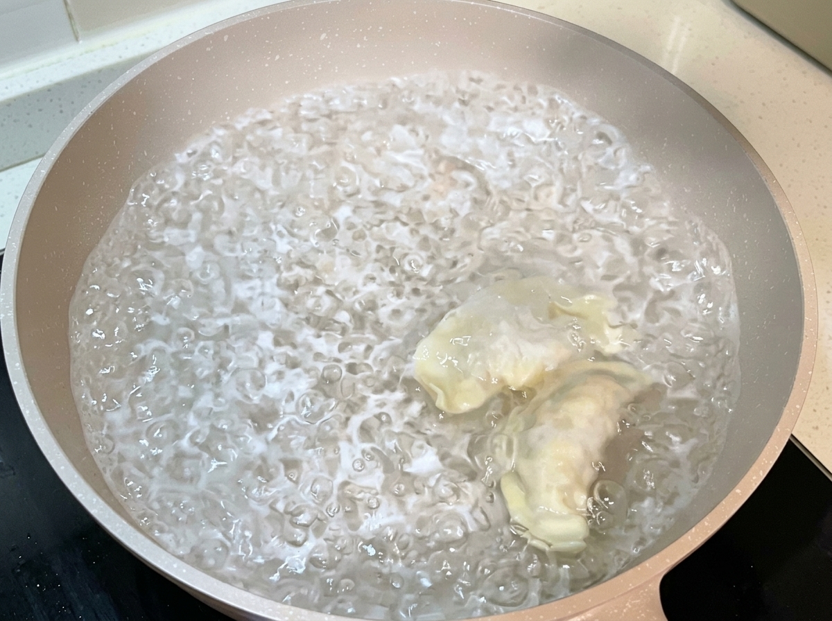 Ravioli avvolti che vengono immersi in una pentola di acqua bollente.