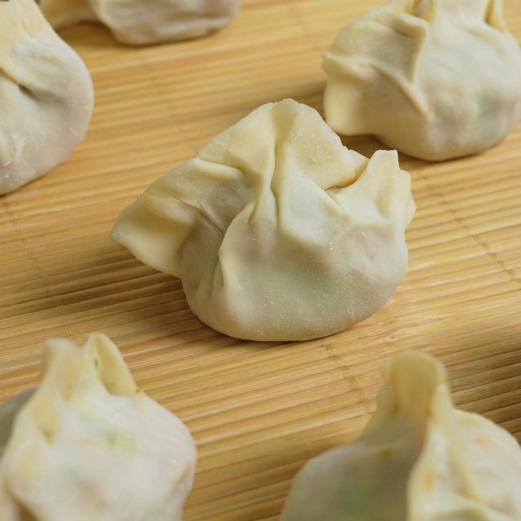 Diversi ravioli preparati vengono immersi in una pentola di acqua bollente per la cottura.