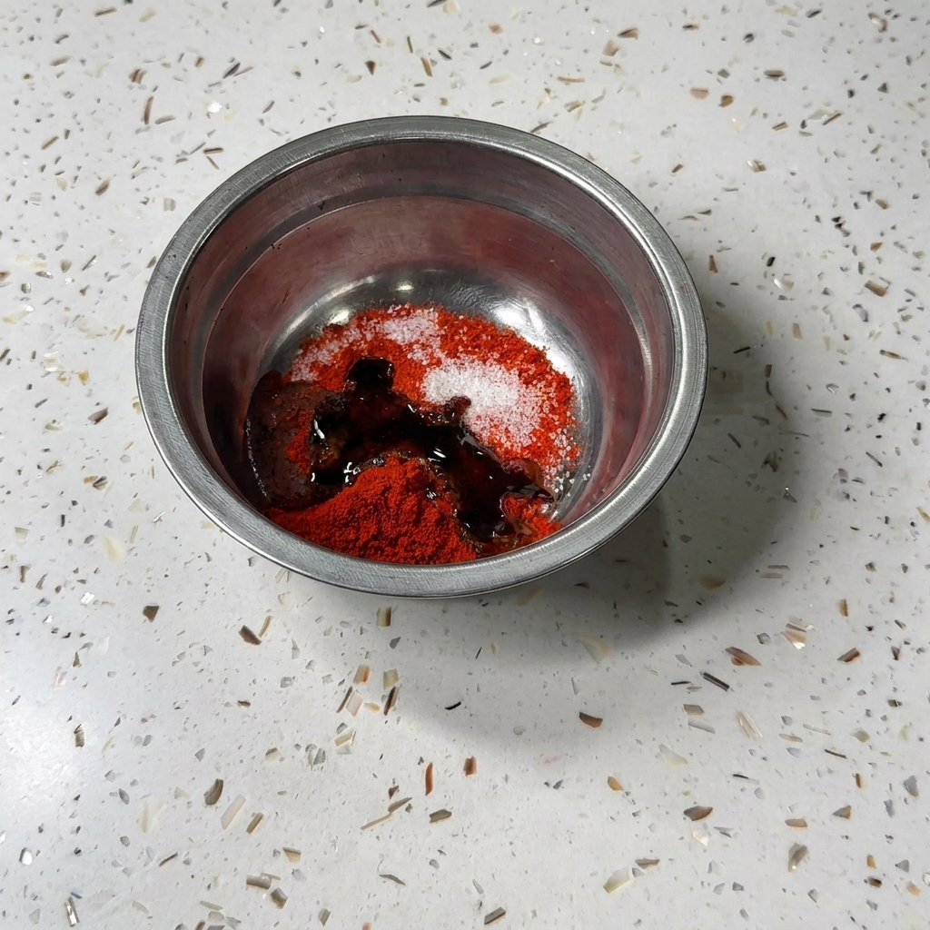 Salsa di soia liquida scura e salsa di ostriche versate nella ciotola di metallo con peperoncino in polvere e zucchero.