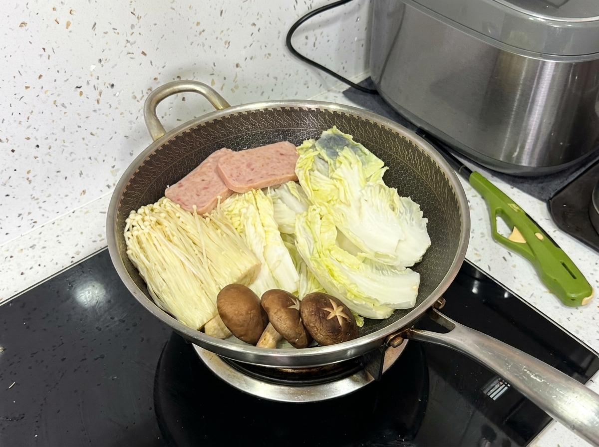 Un wok completamente disposto contenente cavolo napa, funghi enoki, funghi shiitake, carne in scatola e fette di maiale.