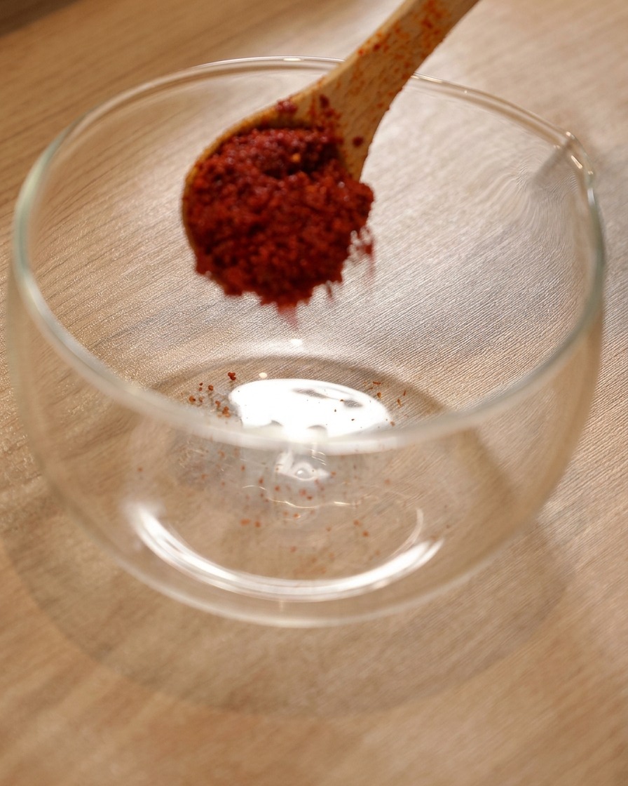 Peperoncino in polvere in una ciotola di vetro con salsa piccante coreana e salsa di soia leggera aggiunte.