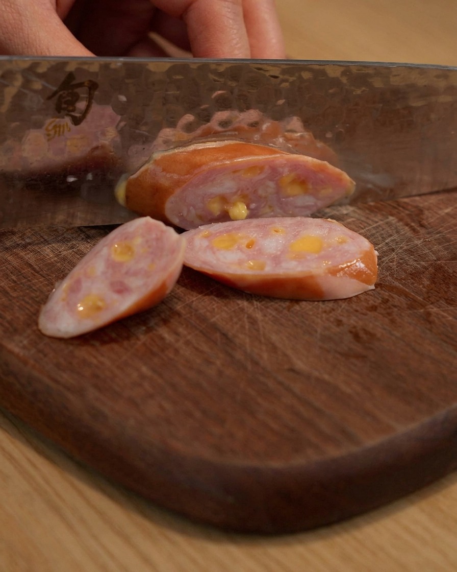 Salsiccia affettata su un tagliere di legno.