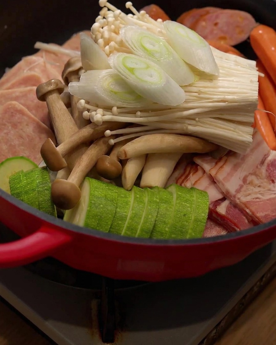 Pezzi di cipollotto appena tagliati posizionati sopra gli ingredienti allinterno dellhot pot.