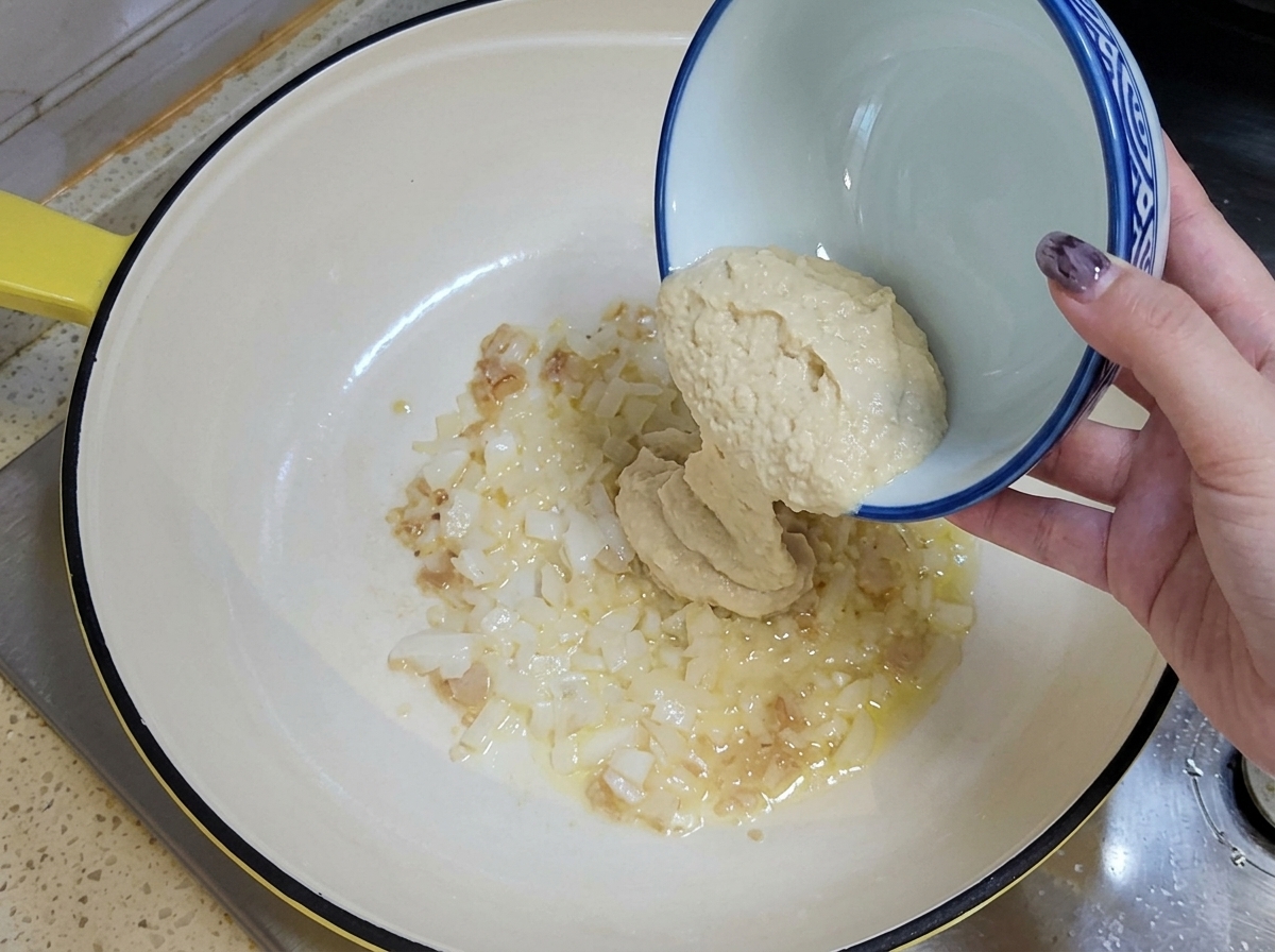 Aglio tritato e cipolla a cubetti versati in una padella oliata da una ciotola in ceramica.