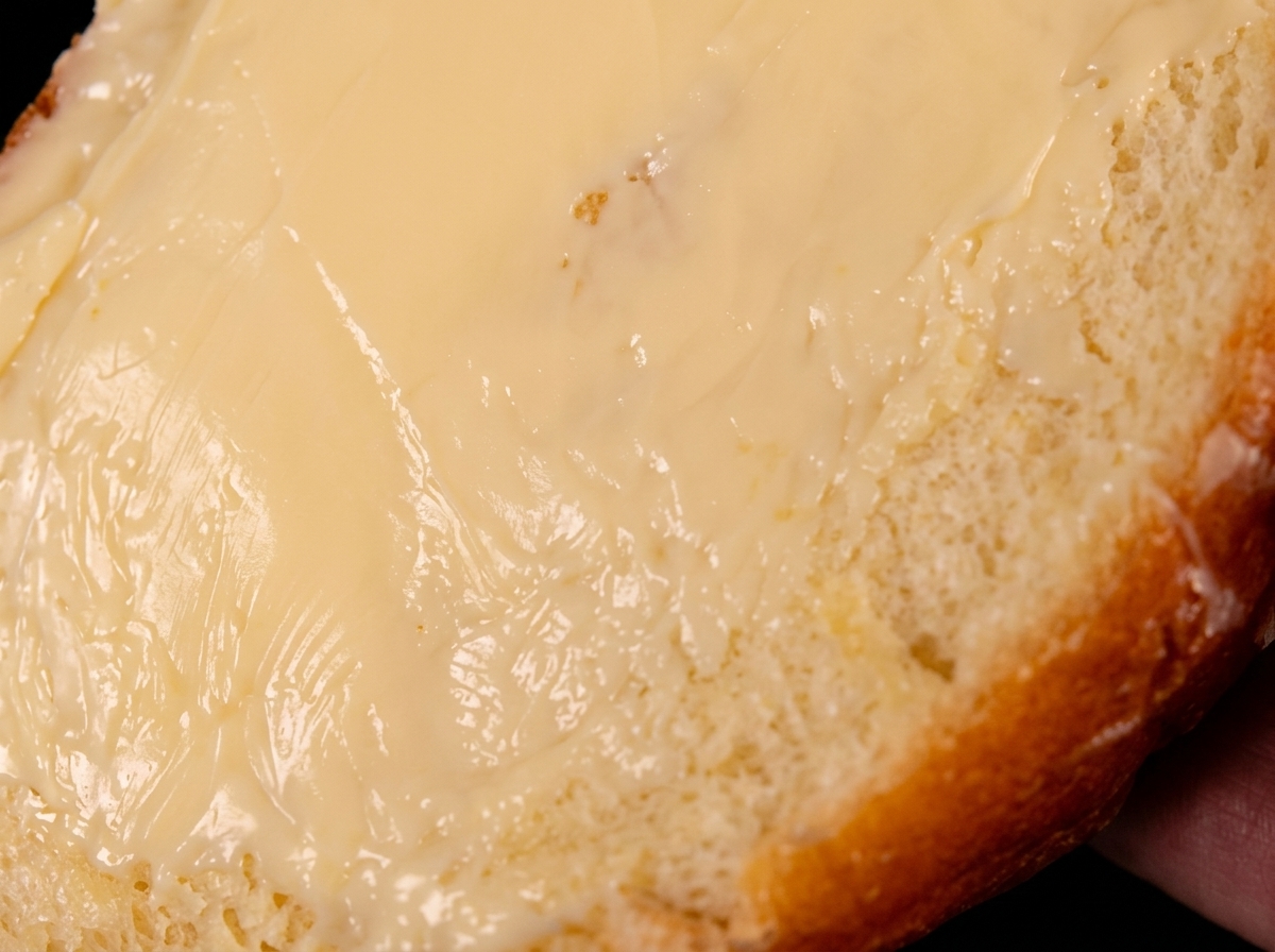 Una singola fetta di pane spalmata di burro, appoggiata con il lato imburrato verso il basso in una padella calda.