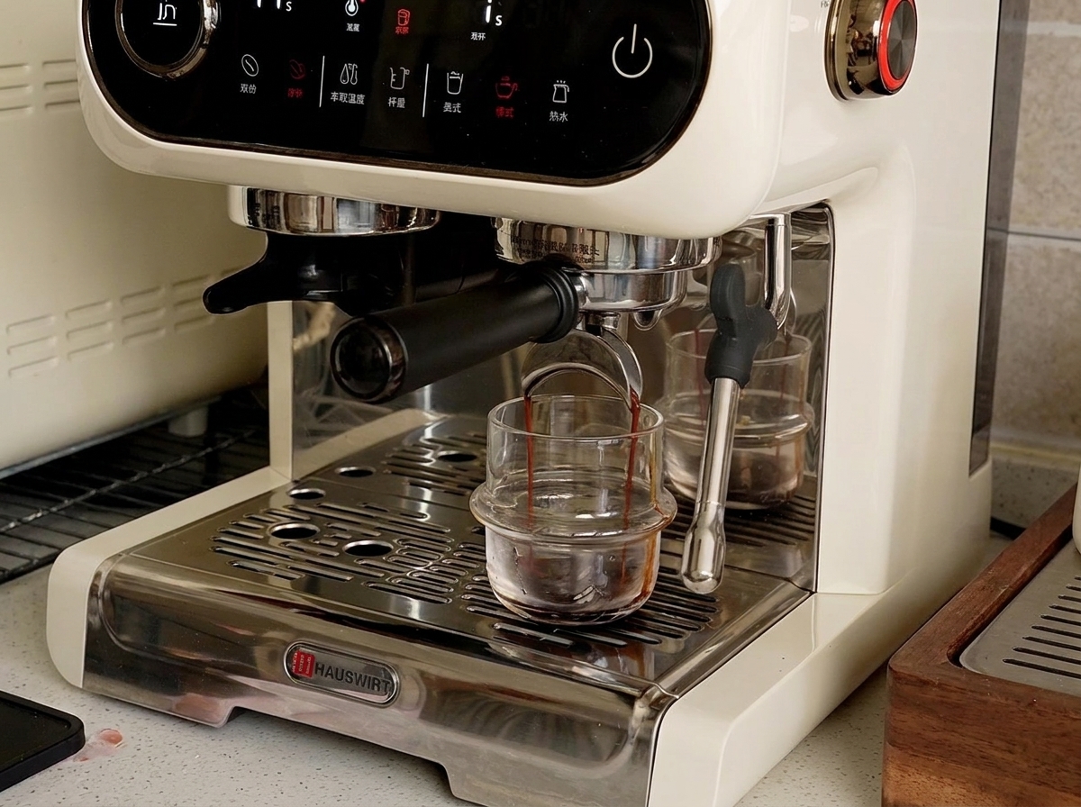 Una macchina da caffè espresso che eroga caffè liquido scuro in una piccola tazza di vetro sul vassoio raccogligocce.