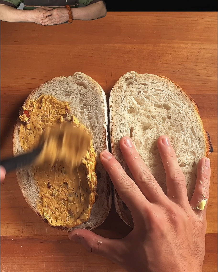Fette di pane di pasta madre rustico con una salsa ricca stesa da un cucchiaio.