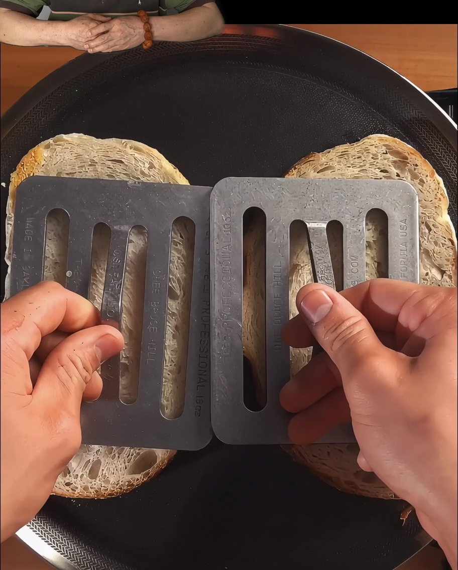 Fette di pane pressate e tostate in una padella nera fino a doratura.