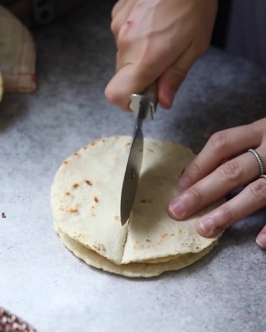 Tortillas cotte impilate tagliate in sezioni triangolari con una lama.