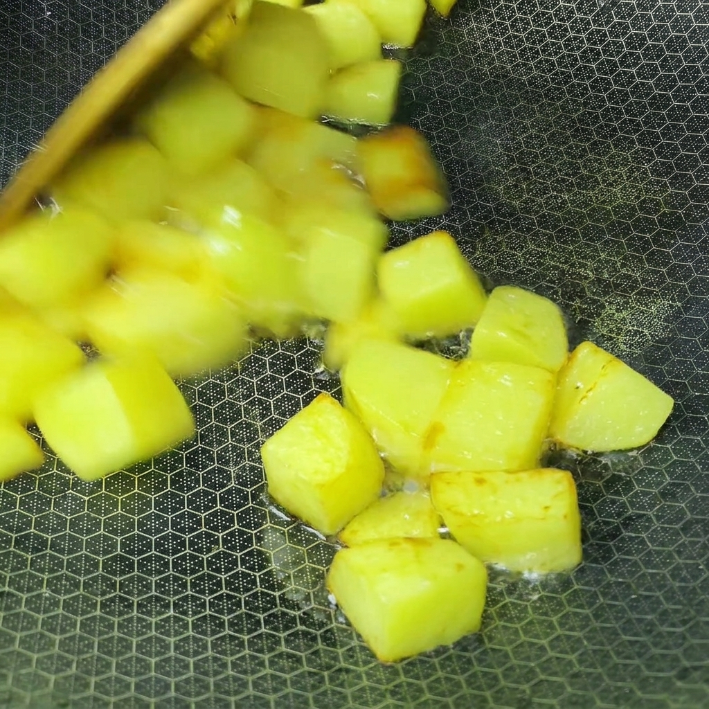Cubetti di patate che friggono nellolio dentro un wok fino a doratura.
