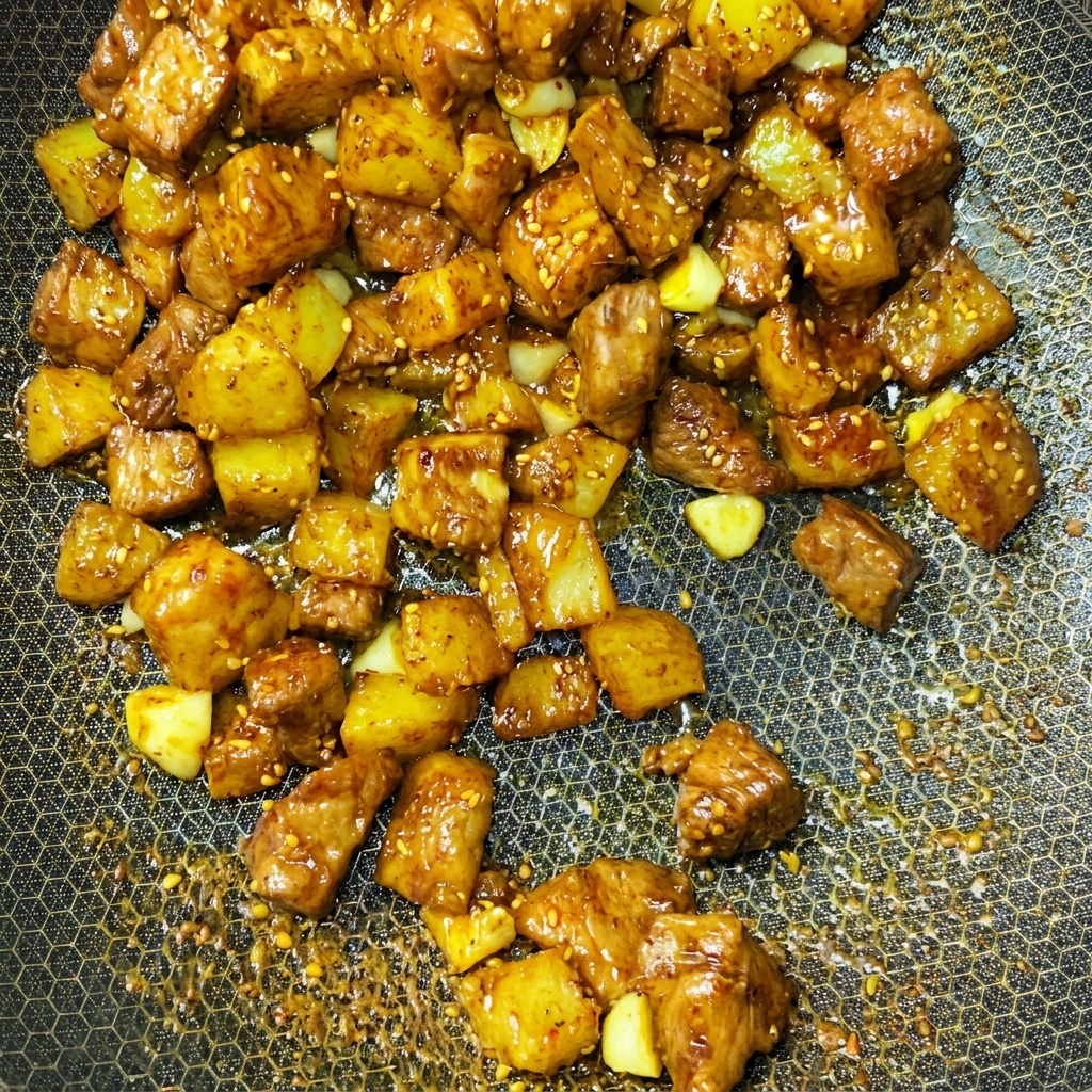 Cubetti di maiale e patate saltati dinamicamente in un wok con le spezie.