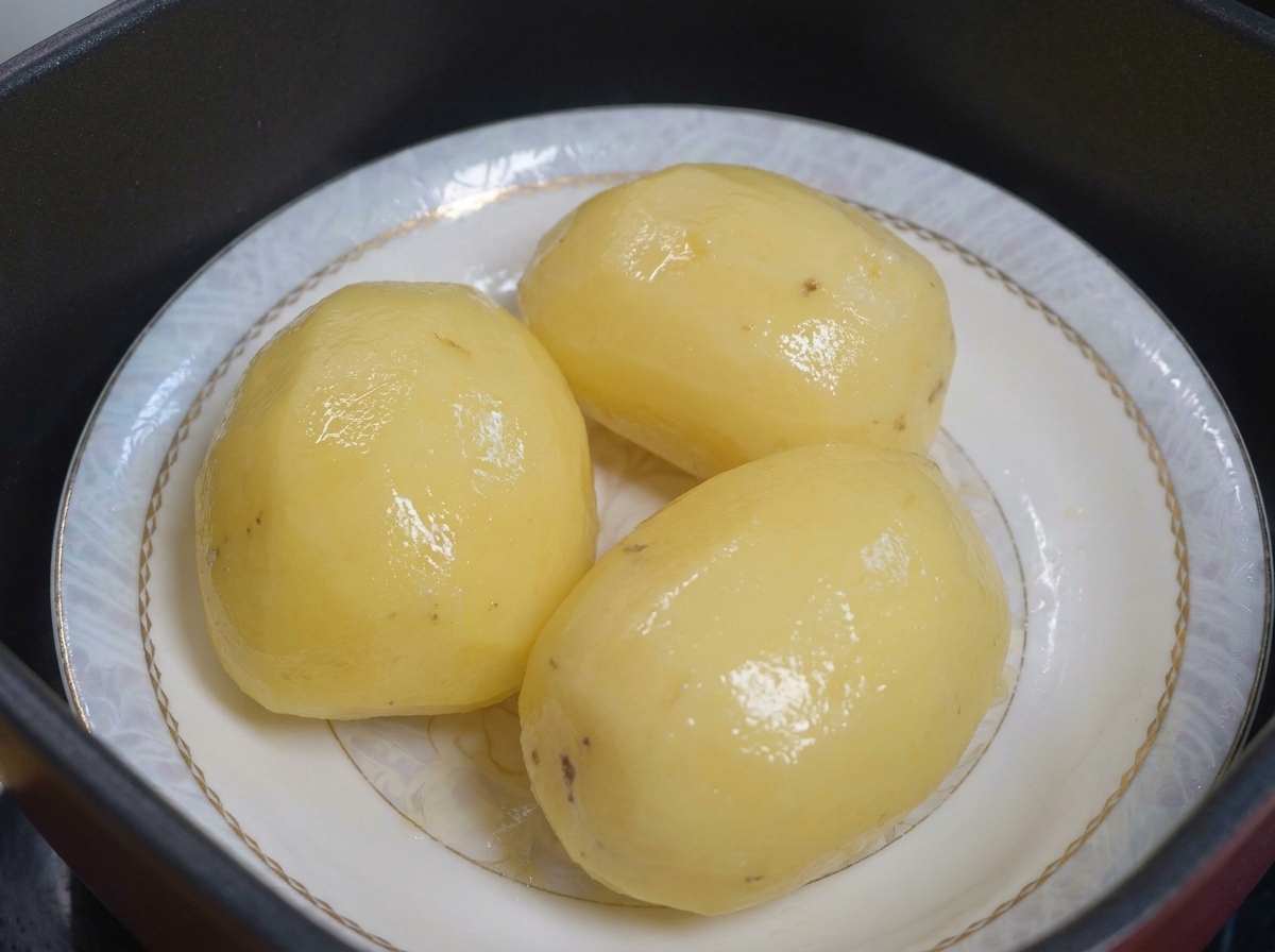 Patate cotte al vapore su un piatto pronte per essere cosparse di olio.