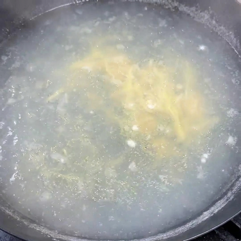 Cipollotti tritati mescolati uniformemente in una pentola di zuppa calda che sobbolle.