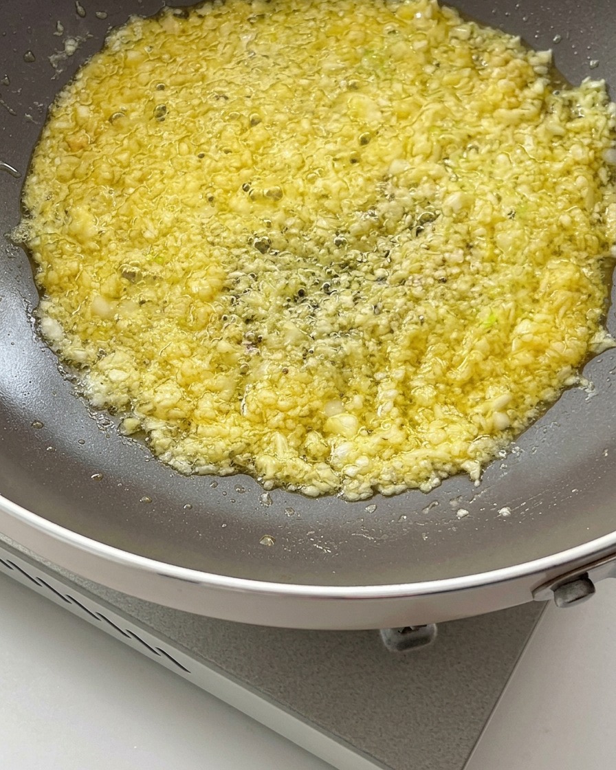 Salsa di soia e salsa dostriche versate nel composto sfrigolante di burro e aglio in una padella.