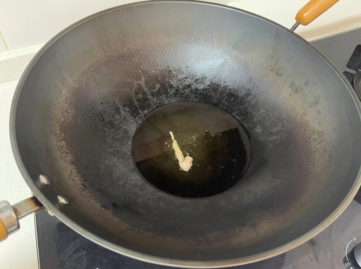 Un singolo pezzo di pollo rivestito che frigge al centro di un grande wok con olio caldo.