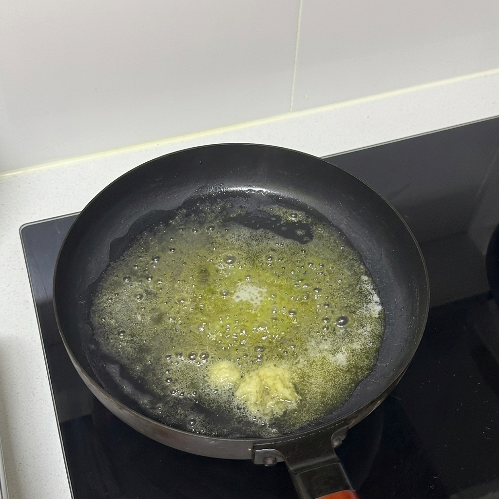 Aglio tritato che cuoce nel burro fuso in una padella.