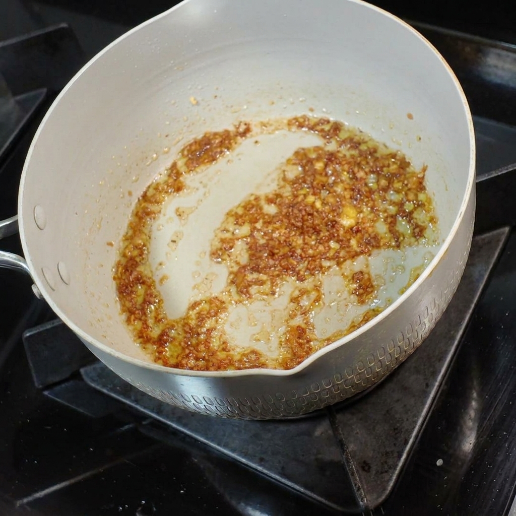 Un piccolo metto di brodo di noodle saporito versato nel composto aromatico di burro e aglio.