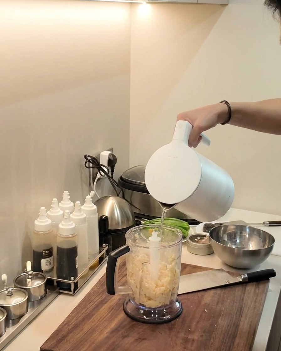 Un frullatore a immersione che riduce in purea il composto di manioca e platano allinterno della caraffa.