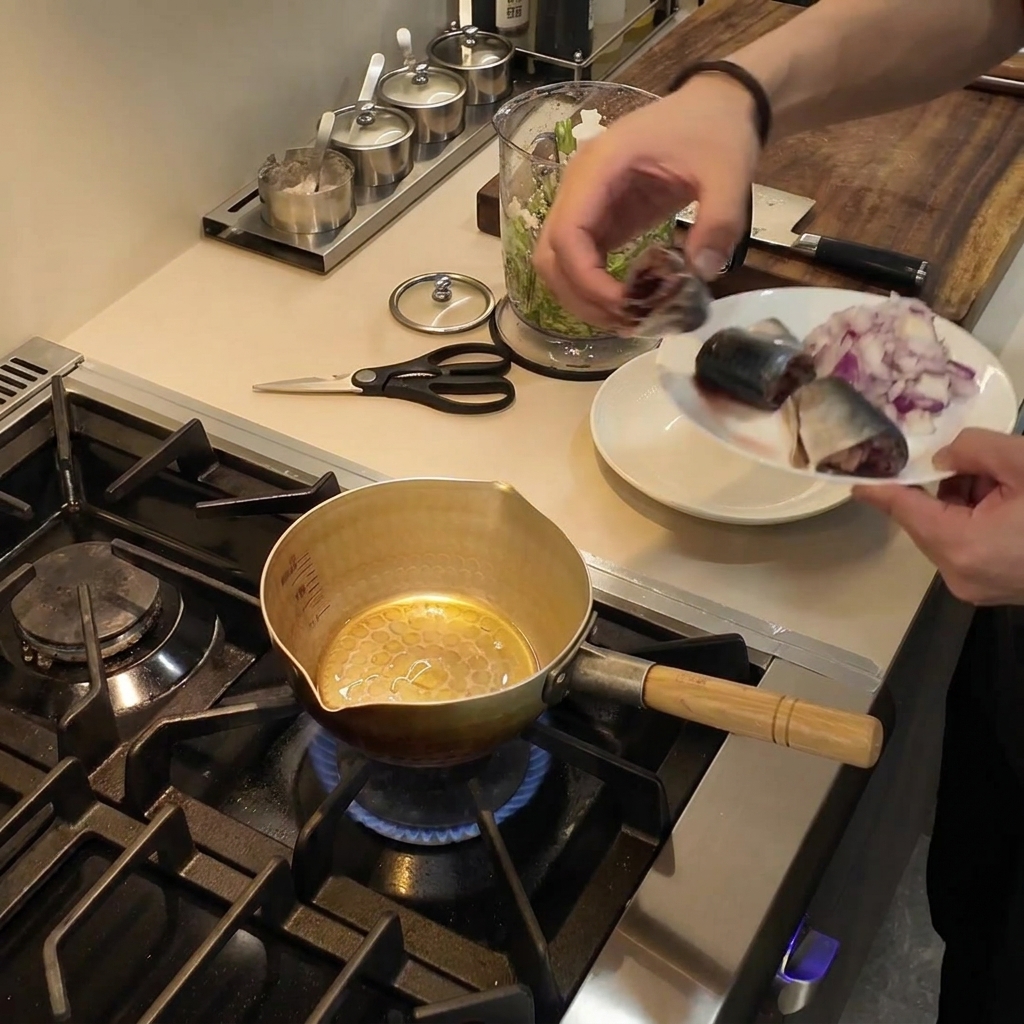 Una piccola pentola dorata posta su un fornello a gas con olio da cucina che scintilla allinterno.