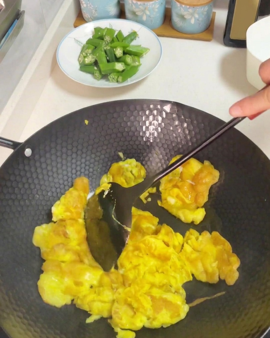 Usare una spatola scura per mescolare e strapazzare le uova cotte in un wok riscaldato.