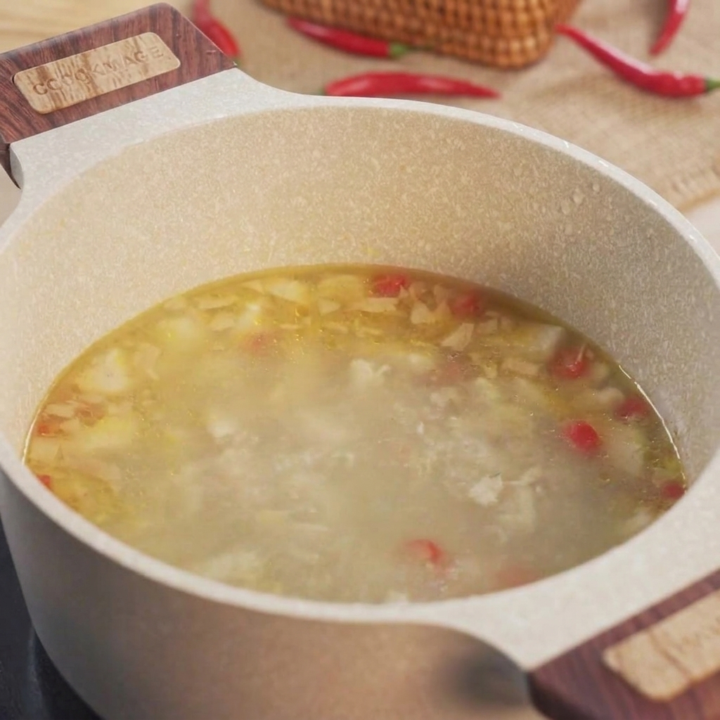 Fette di okra verde messe in una pentola piena di brodo di pollo in ebollizione.