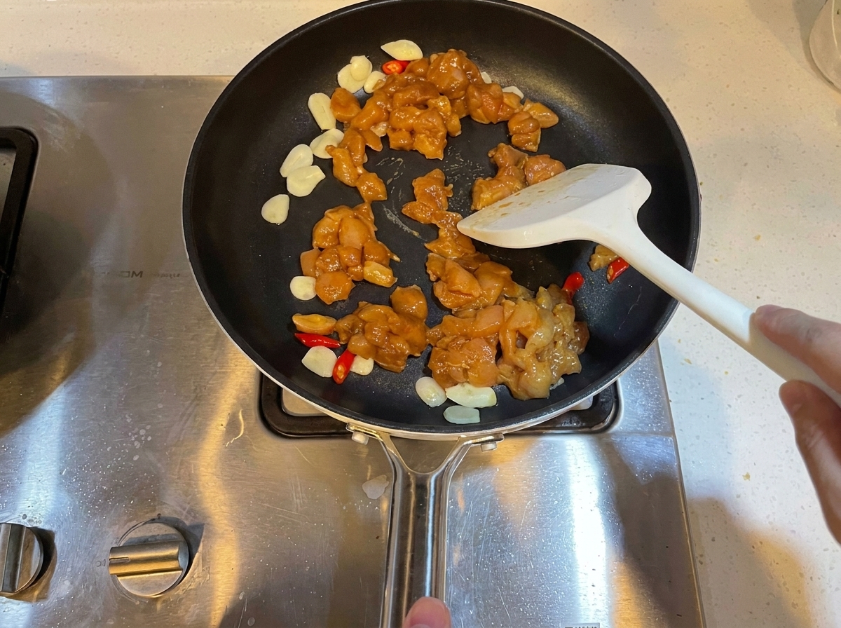 Pezzi di pollo marinato a cubetti saltati in padella con aglio e peperoncini.