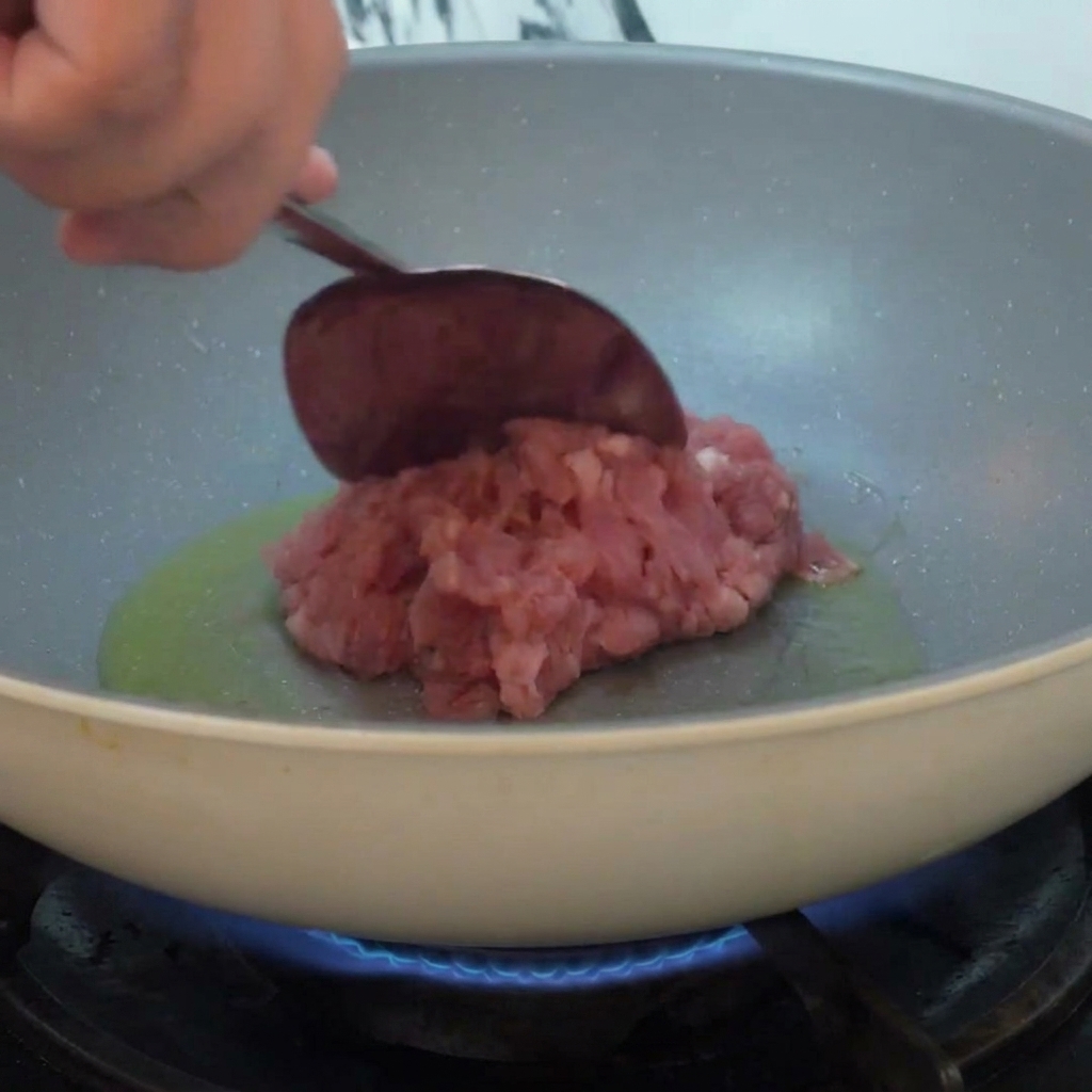 Carne macinata aggiunta in una padella con olio caldo e saltata a fiamma viva.