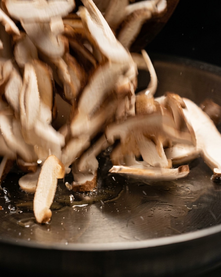 Fette di funghi crudi saltate e aggiunte in una padella di cottura calda.