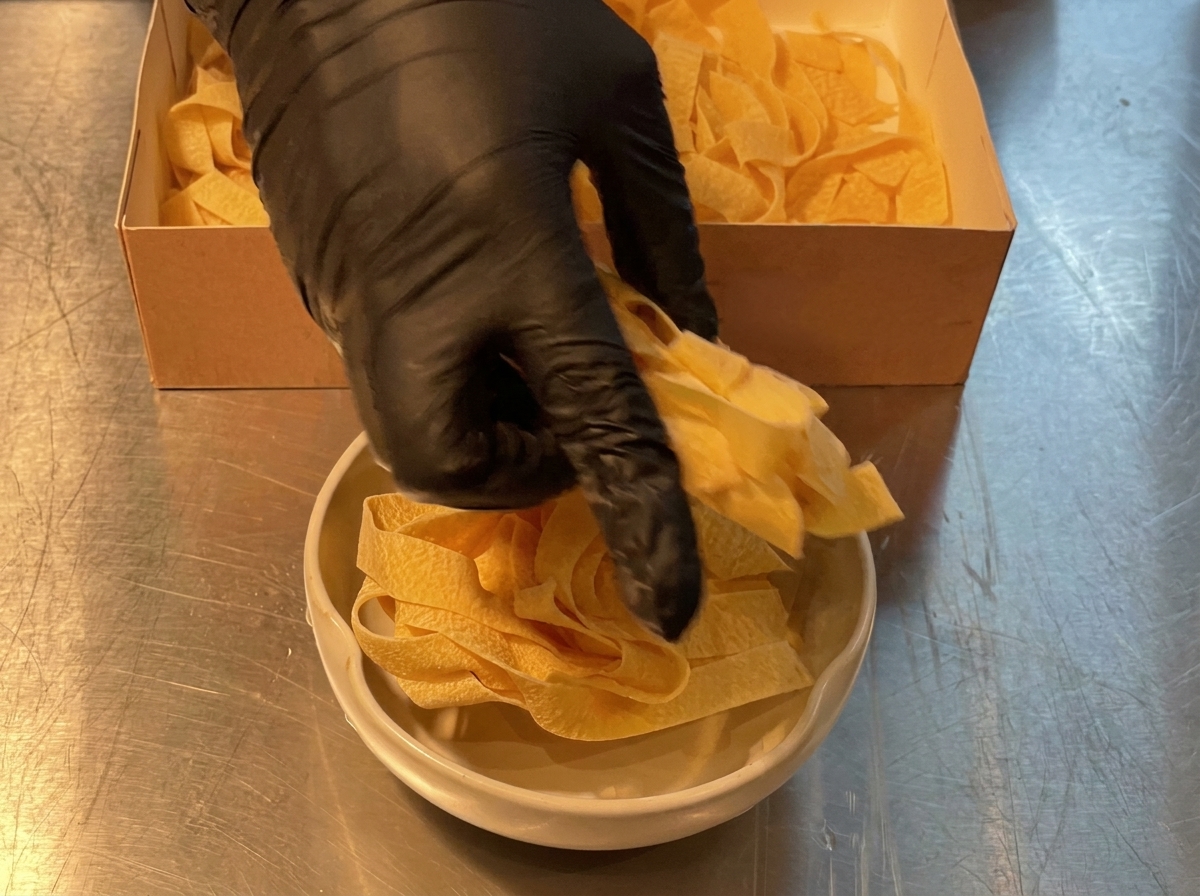Formato di pasta larga porzionato da una scatola di cartone in una ciotola di cottura.