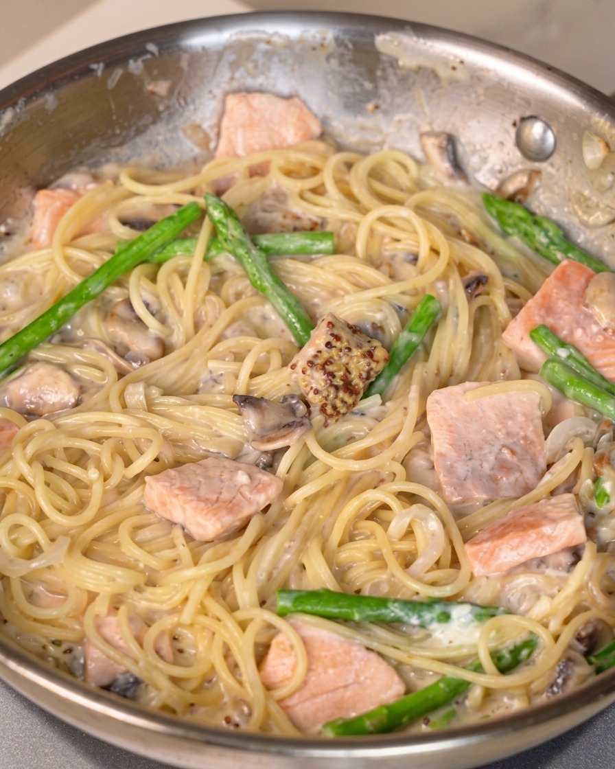 Salsa di senape, sale e pepe mescolati in una padella di pasta cremosa al salmone.