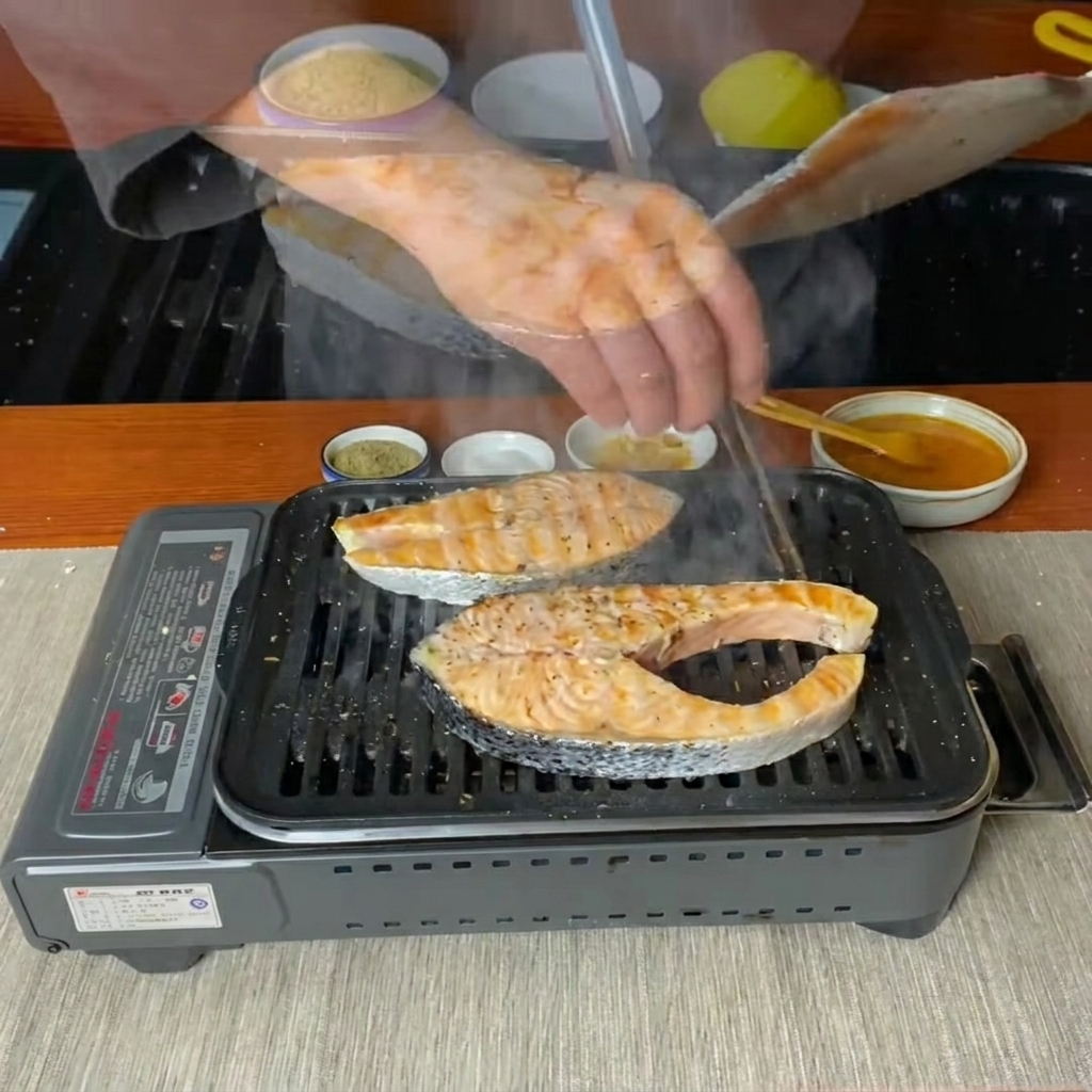 Tranci di salmone rigirati con una spatola su una piastra calda.