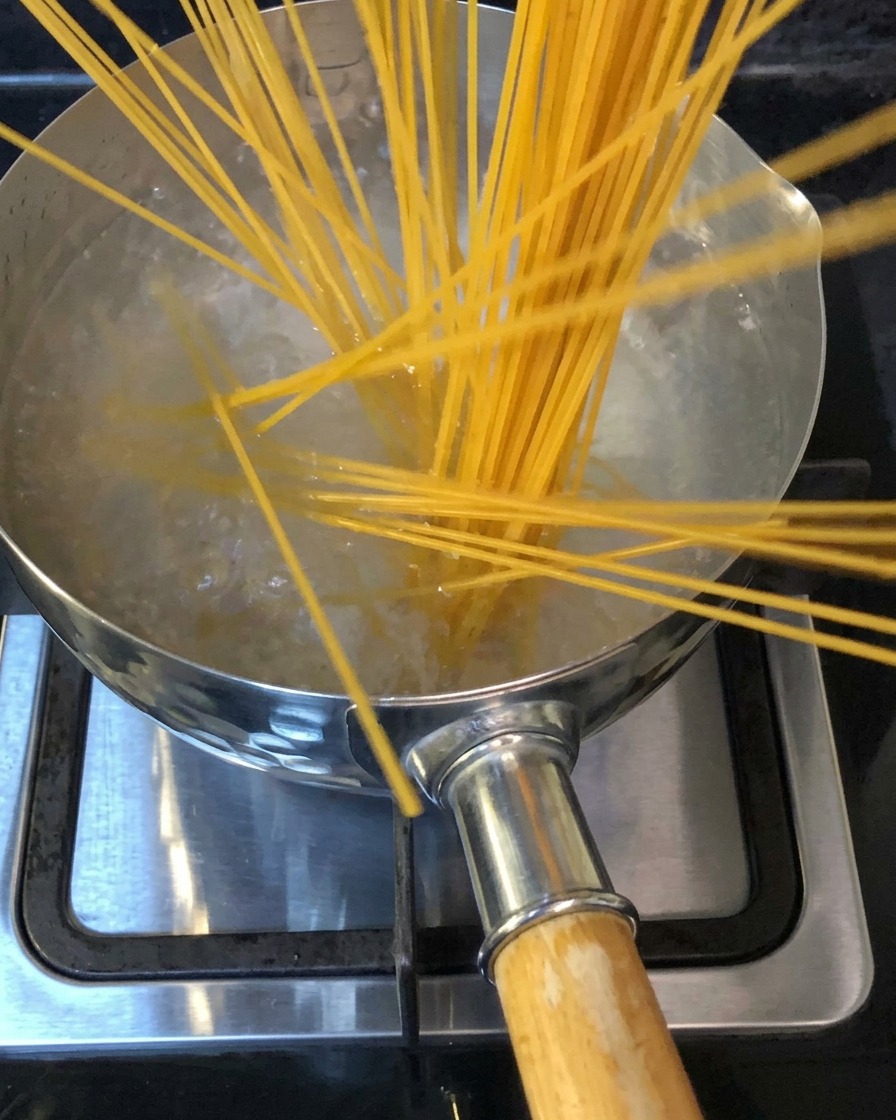 Spaghetti immersi in una pentola di acqua bollente salata sui fornelli.