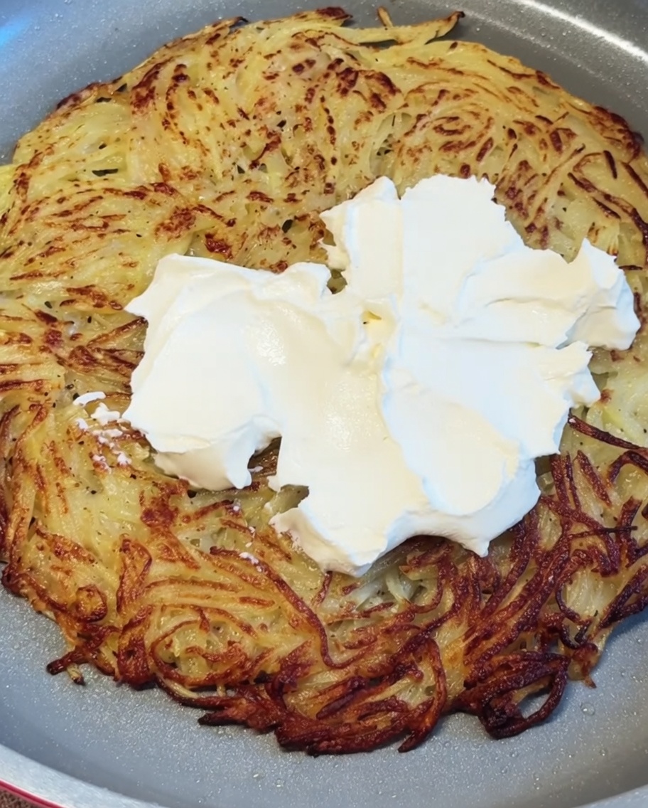 Formaggio cremoso bianco distribuito a cucchiaiate e spalmato sulla frittella di patate ancora calda.