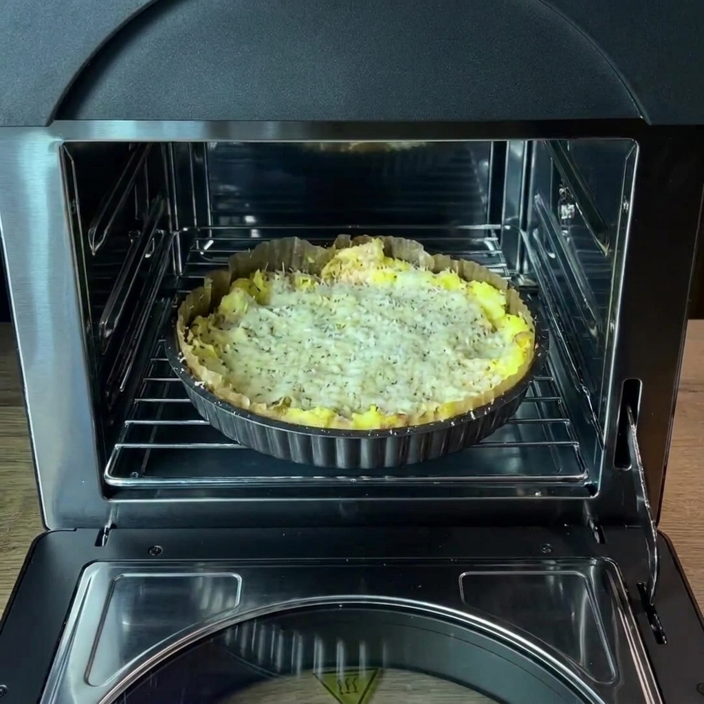 La teglia con la crosta di patate condita posizionata sulla griglia allinterno del forno.