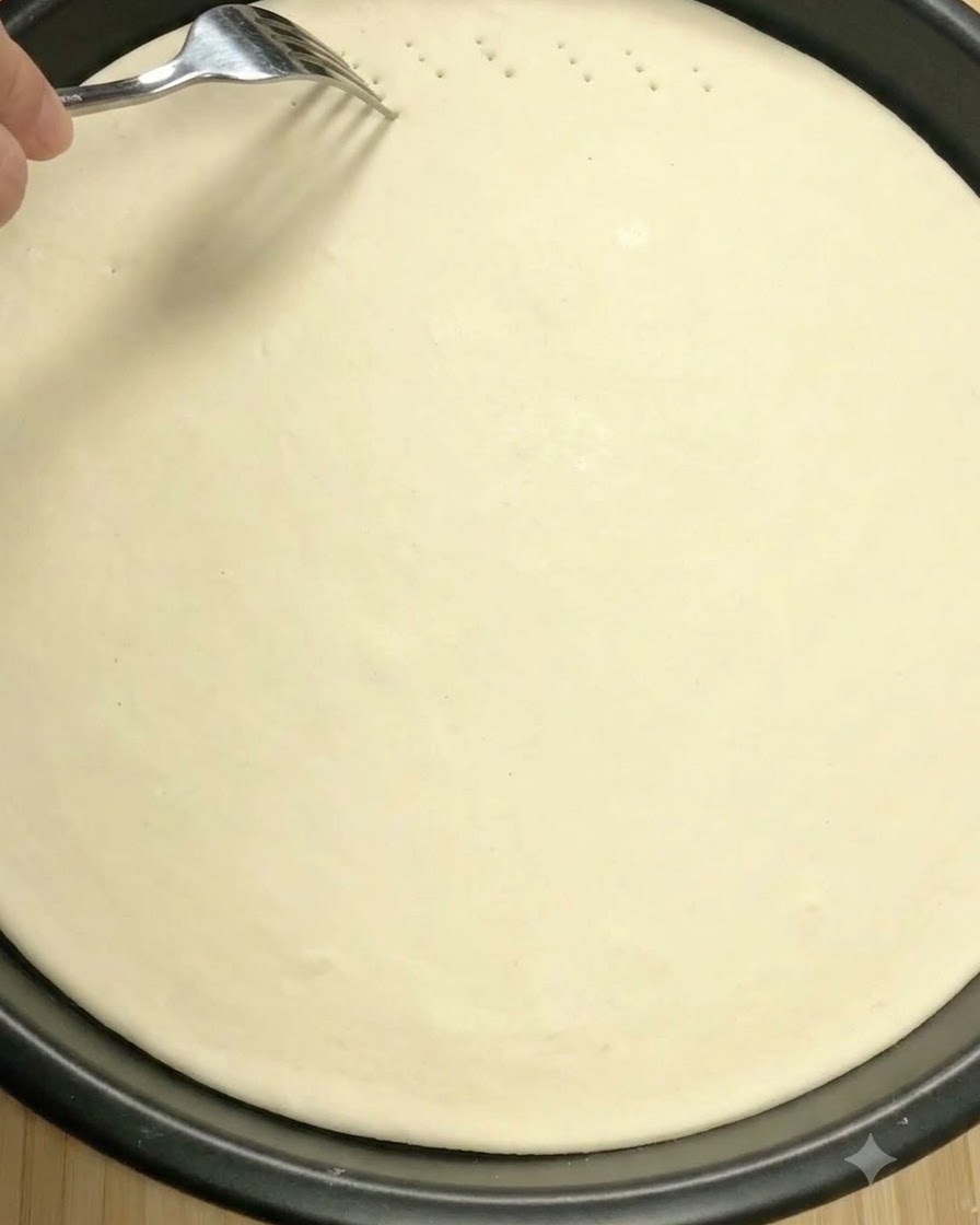 Una forchetta di metallo che fora la superficie della pasta per pizza cruda per creare piccoli sfiati.
