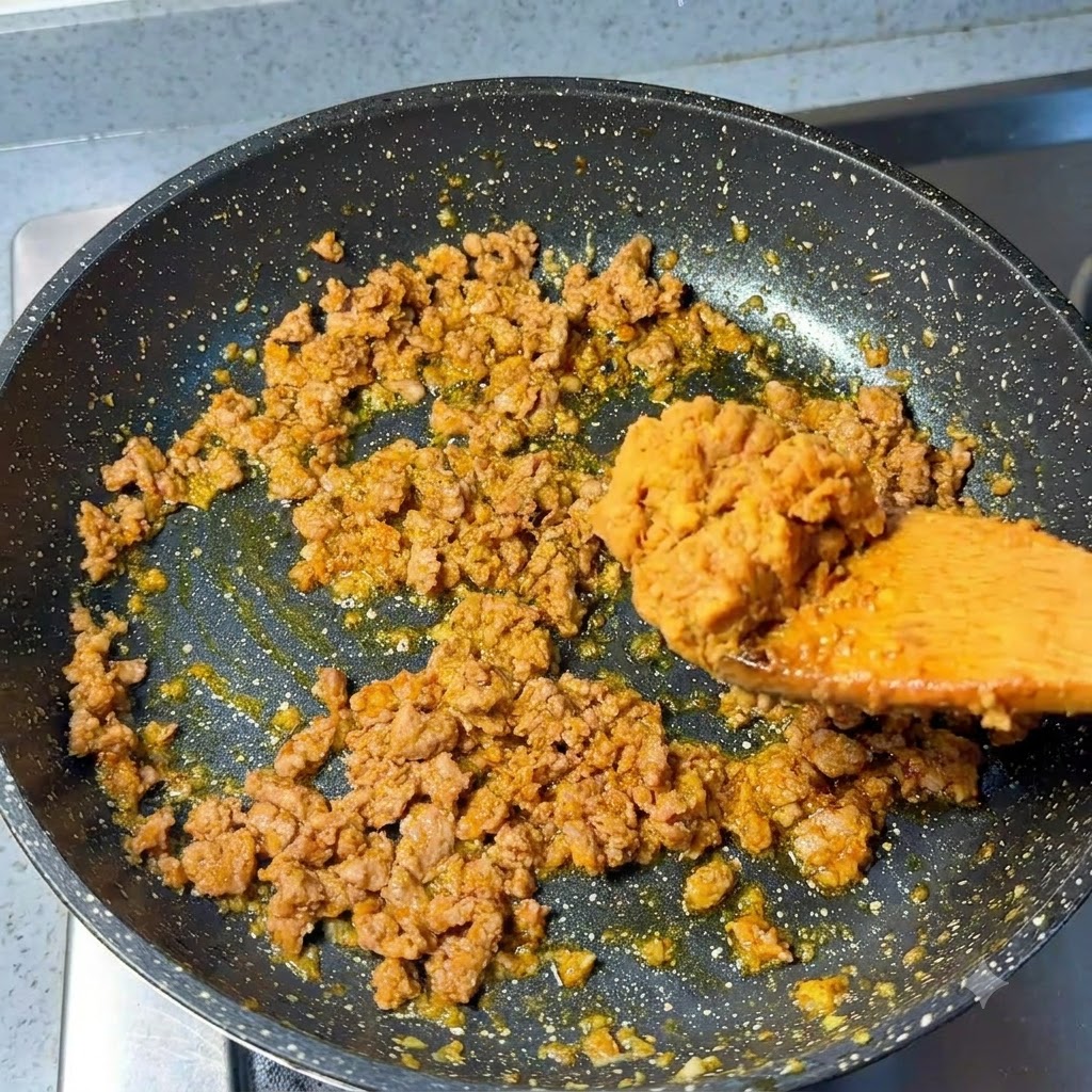 Un cucchiaio di pasta di miso aggiunto al maiale macinato cotto in padella.