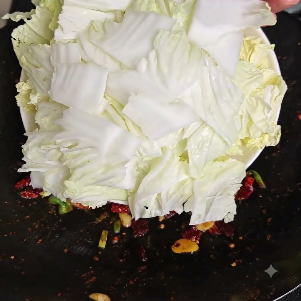 Pezzi di cavolo cinese crudo fresco appena versati da un piatto bianco in un wok caldo.