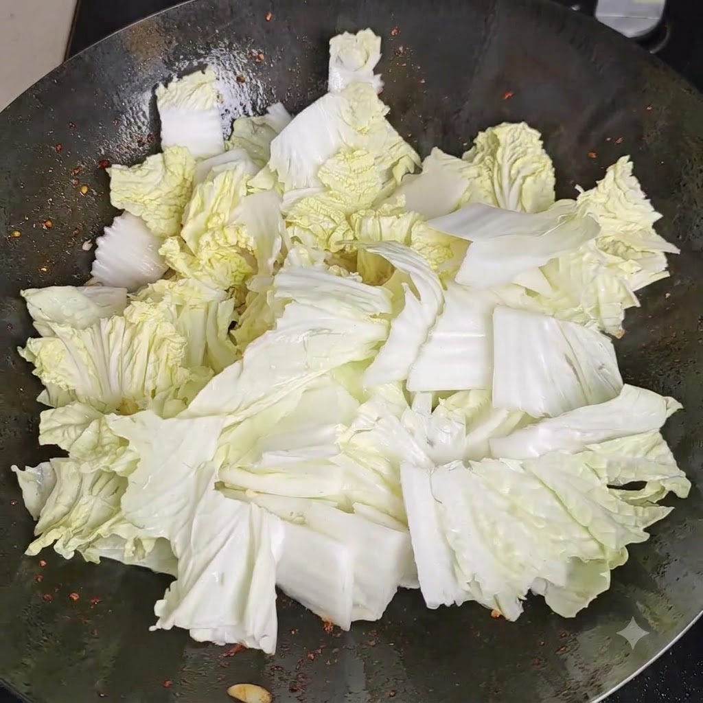 Sale spruzzato uniformemente su un mucchio di pezzi di cavolo cinese fresco allinterno di un wok.