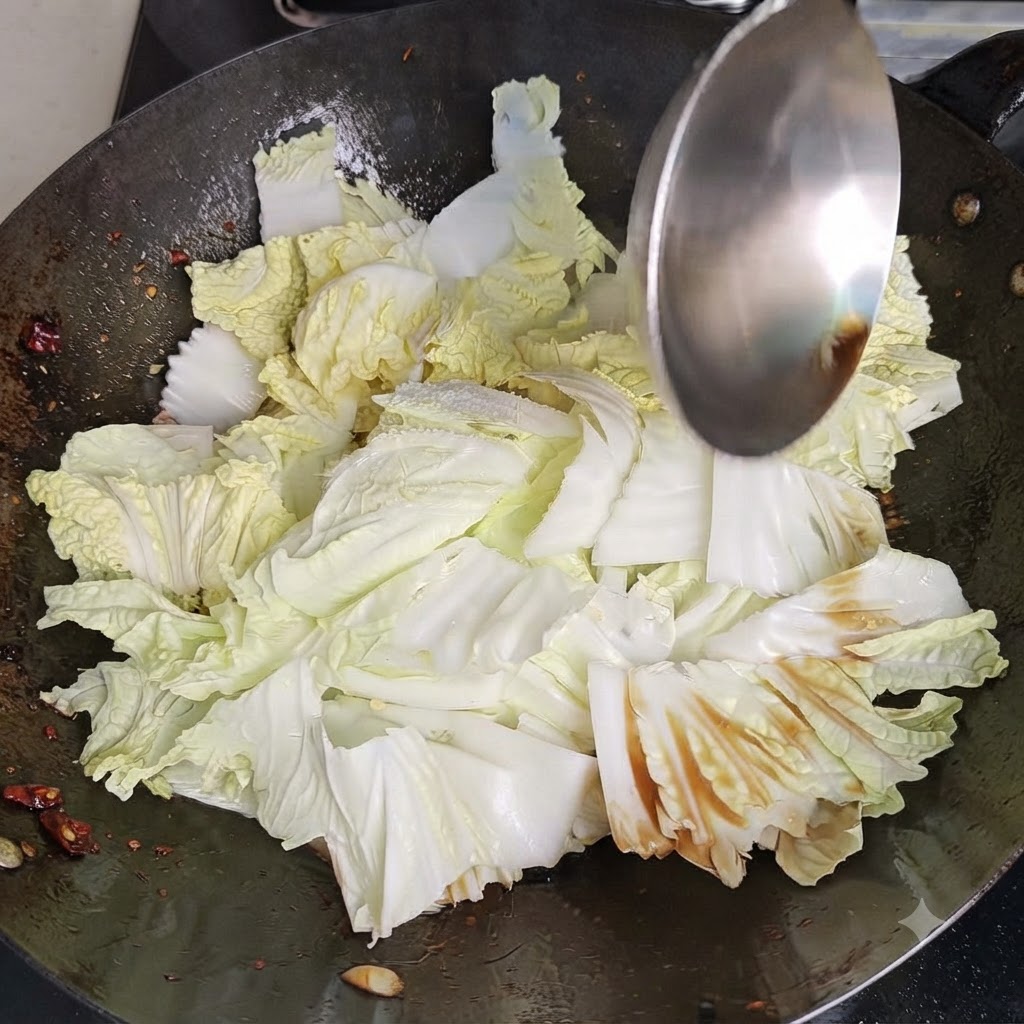 Una spatola da wok di metallo che mescola e gira cavolo cinese e condimenti vigorosamente allinterno di un wok caldo.